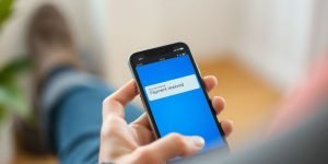 Käsi pitää älypuhelinta, jossa näkyy tilisiirto.