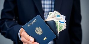 Henkilö pitää passia ja rahaa kädessä.